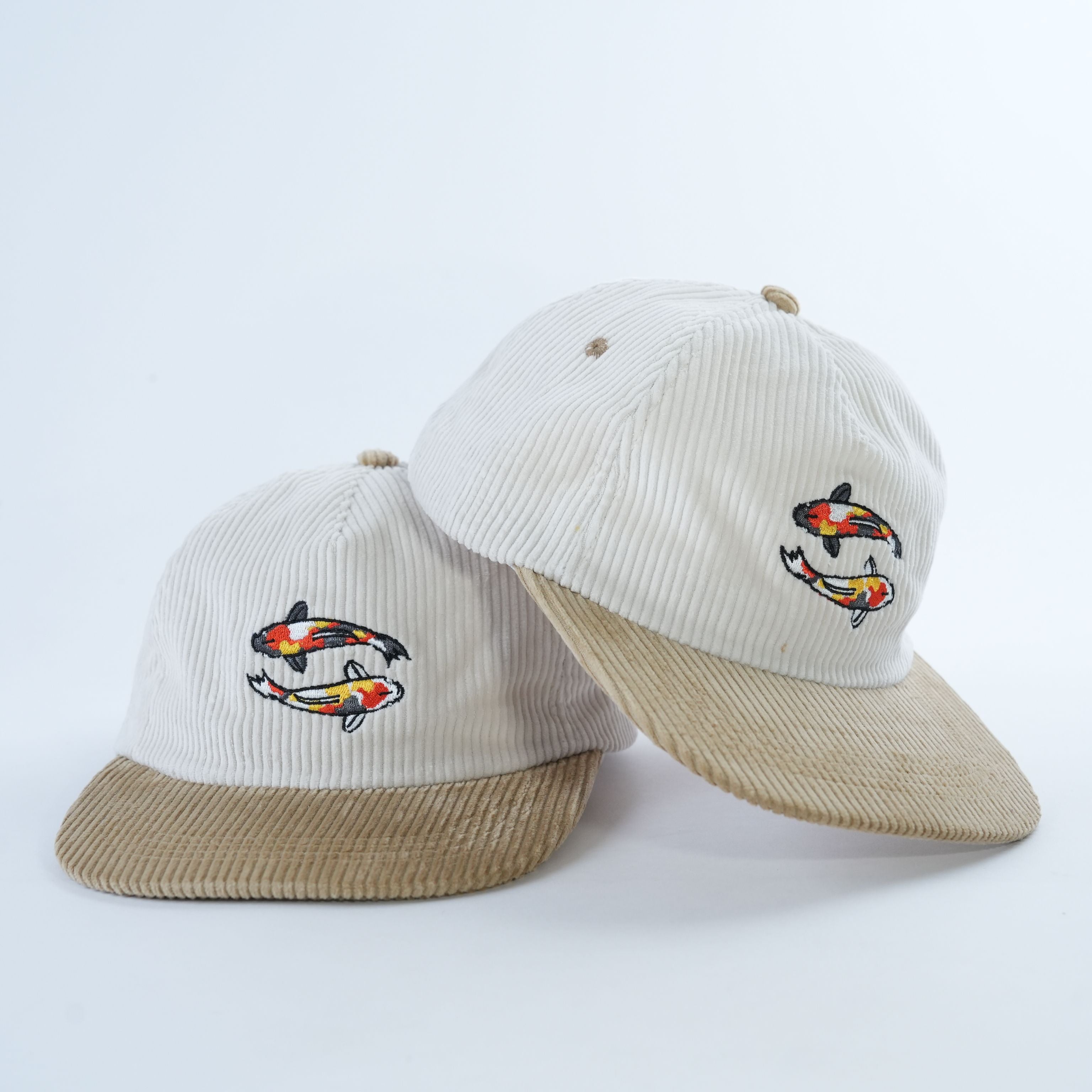 Bucket hat on white background. Light blue corduroy with crane embroidery on one side, with pink and purple origami crane pattern on reversible side