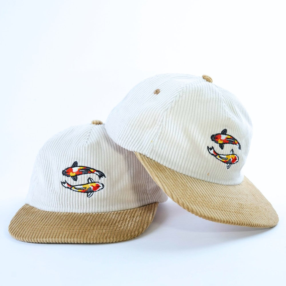 Two hats with koi fish designs in corduroy material on a white background