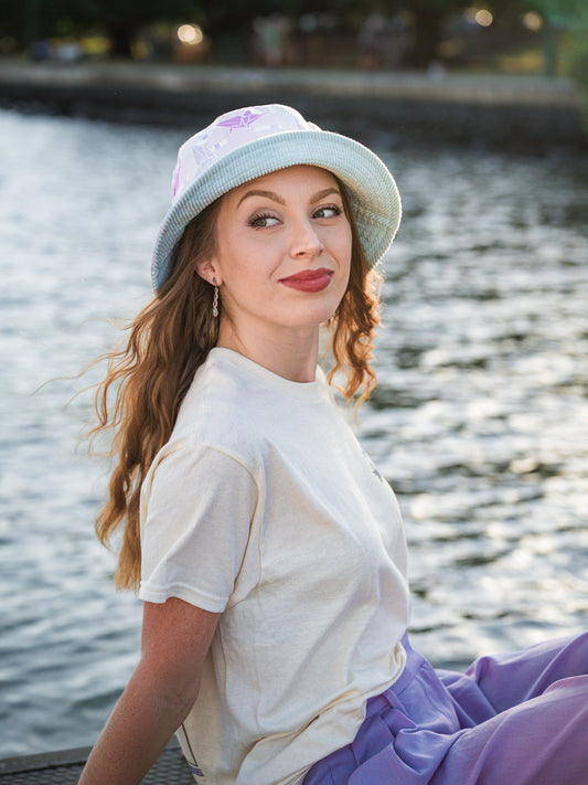 Woman wearing a light blue bucket hat by a body of water