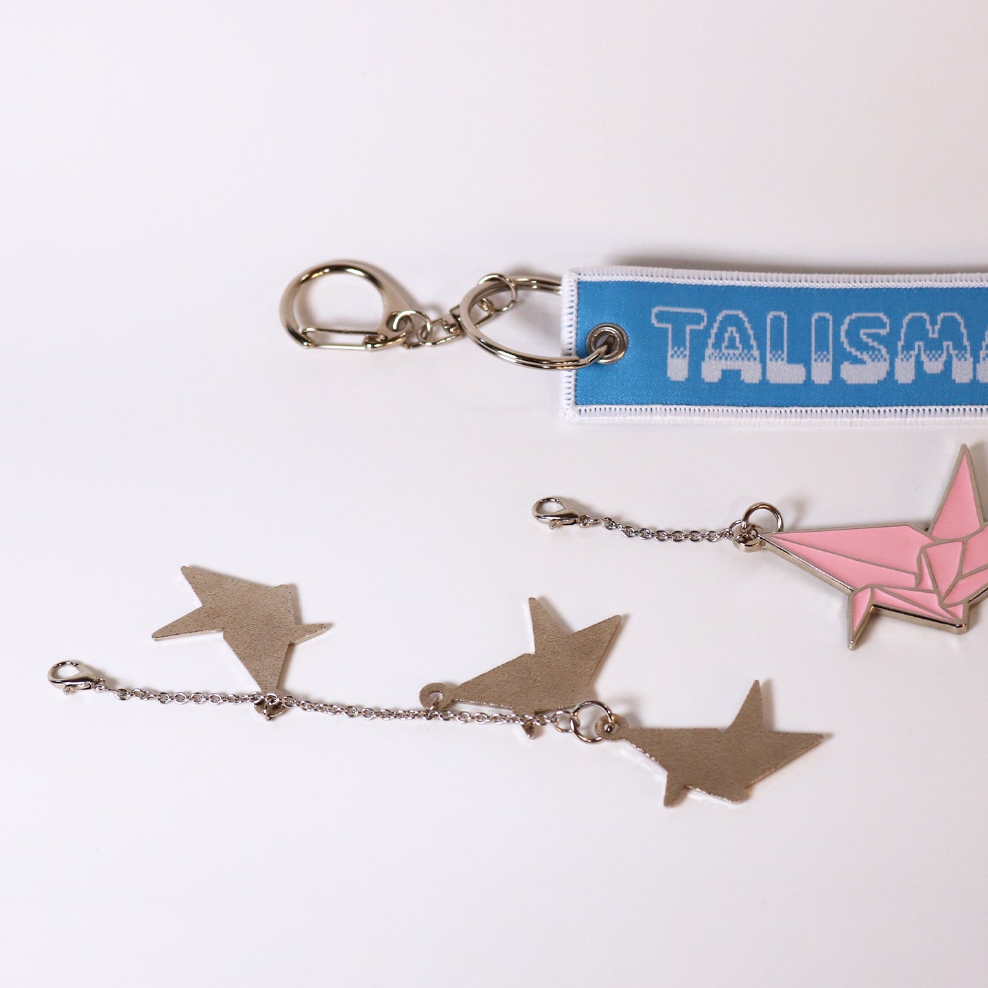 Origami crane keychain and woven blue tag keychain on a white background